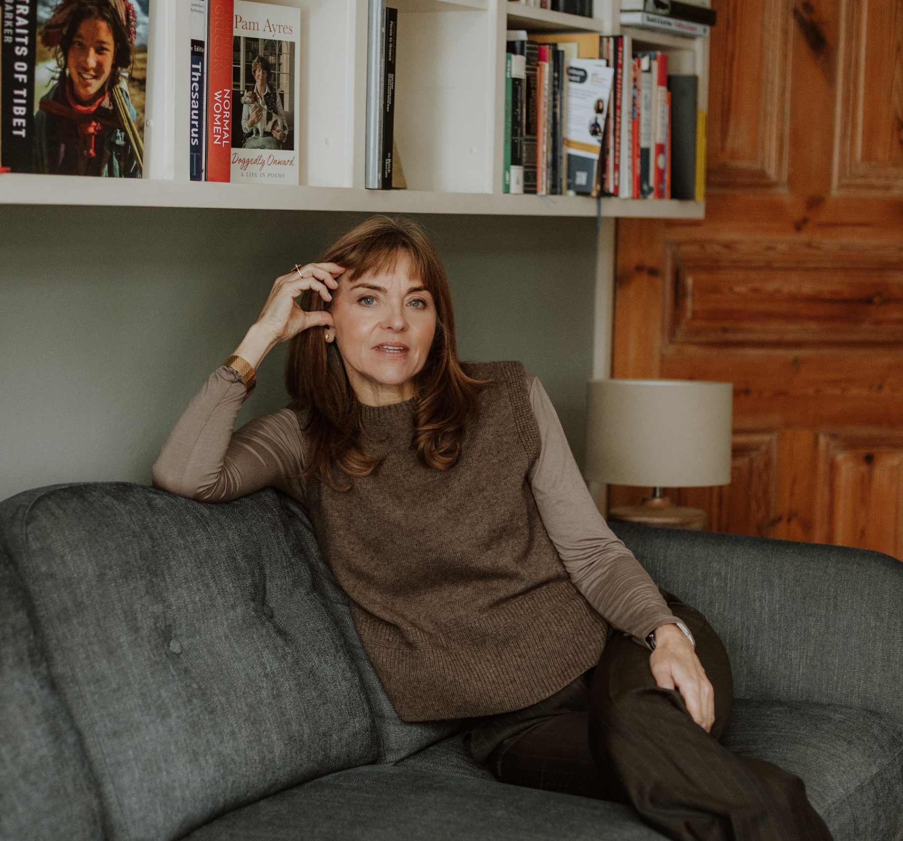 Rachel Ellison MBE seated on a sofa in a calm, book-lined room